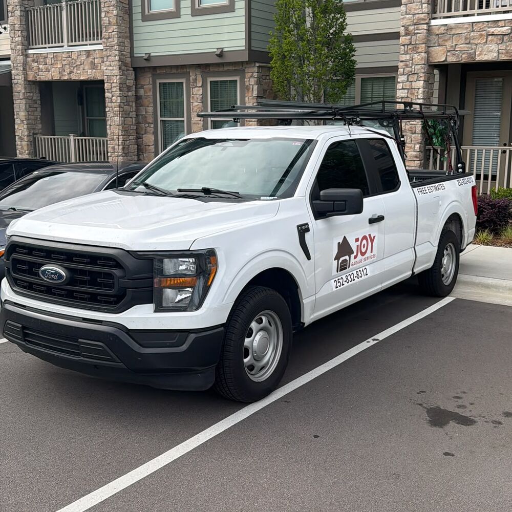 White Joy Garage Services pickup truck with the company logo and phone number on the door