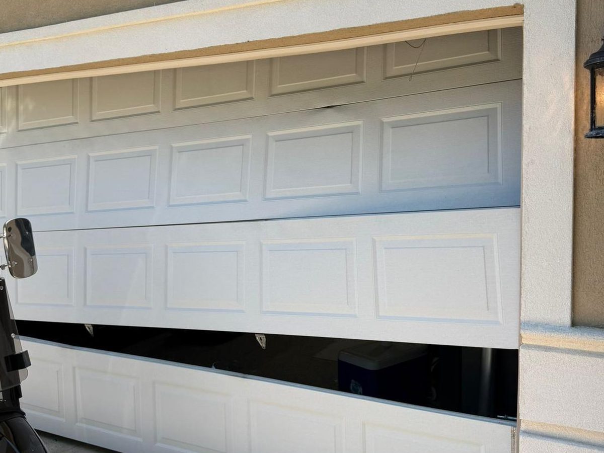 Residential garage door with sections knocked out of line by an impact – Joy Garage Services job