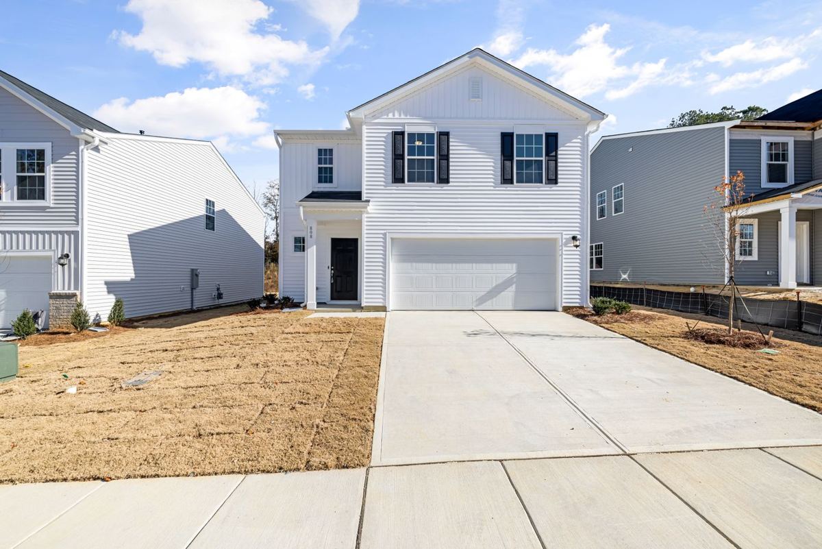 A two-story house with a white garage door and a concrete driveway