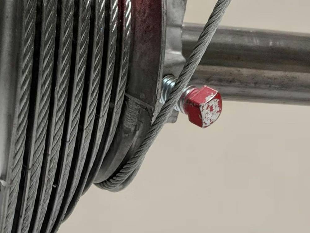 Lift cable wound on a garage door cable drum at the end of the torsion bar