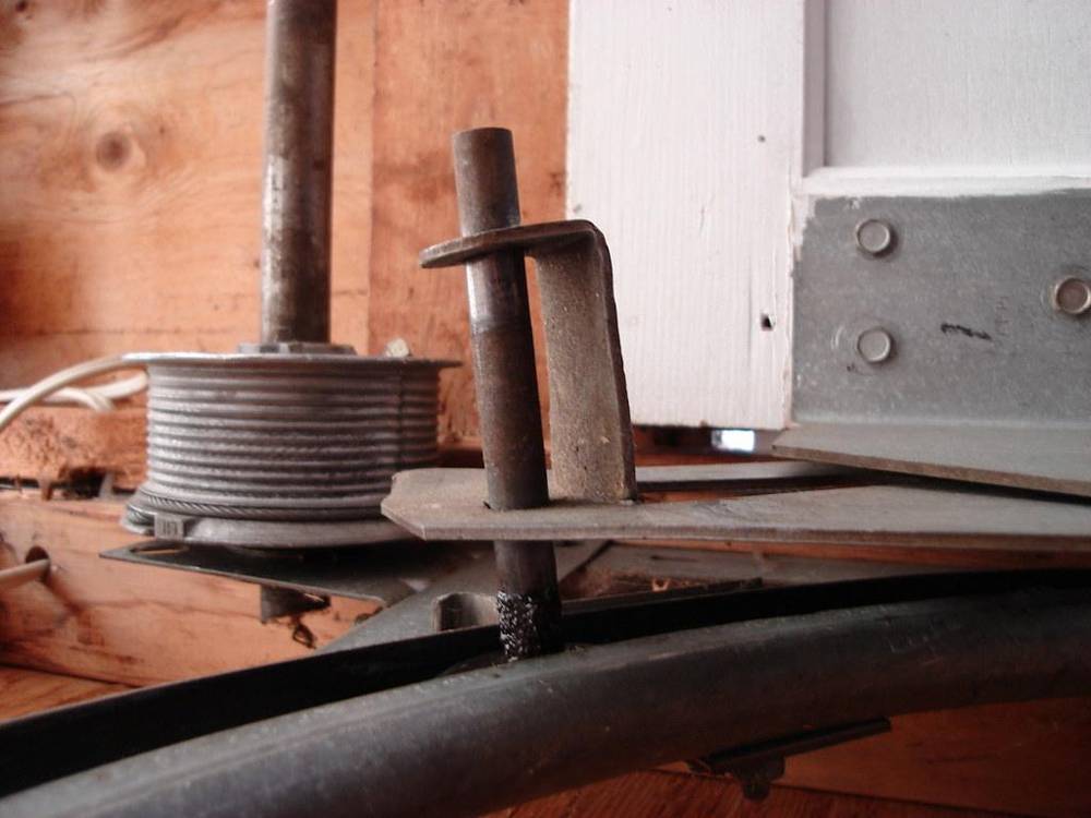 Garage door cable drum and bracket at the top corner of a door