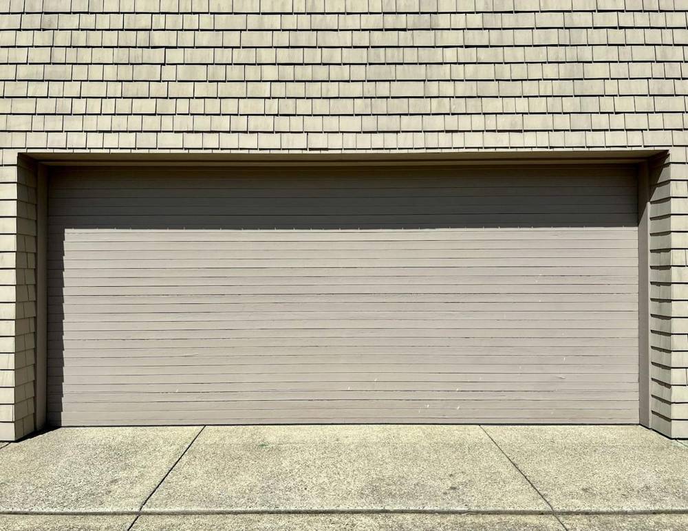 Closed gray sectional garage door with shingle siding