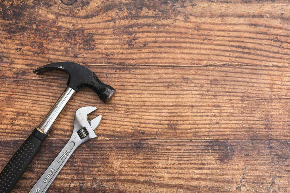 Hammer and adjustable wrench on a wooden table