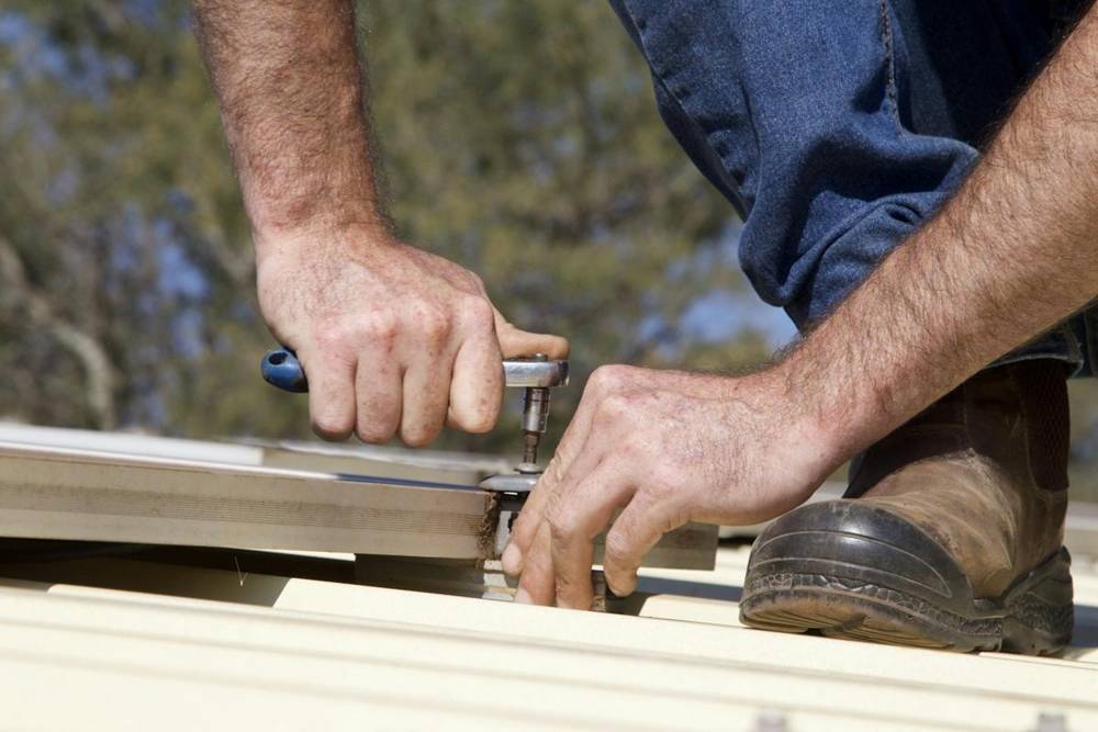 Hands working on a garage door part with a tool