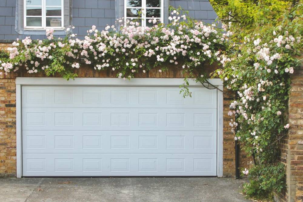 White garage door framed by climbing roses