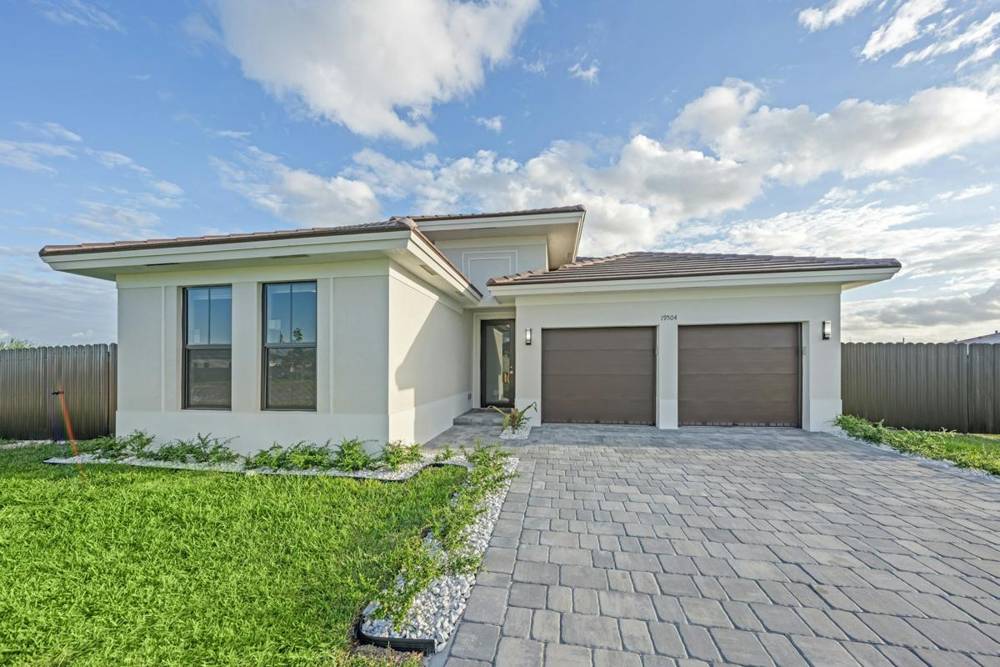 White home with two brown garage doors and a paver driveway